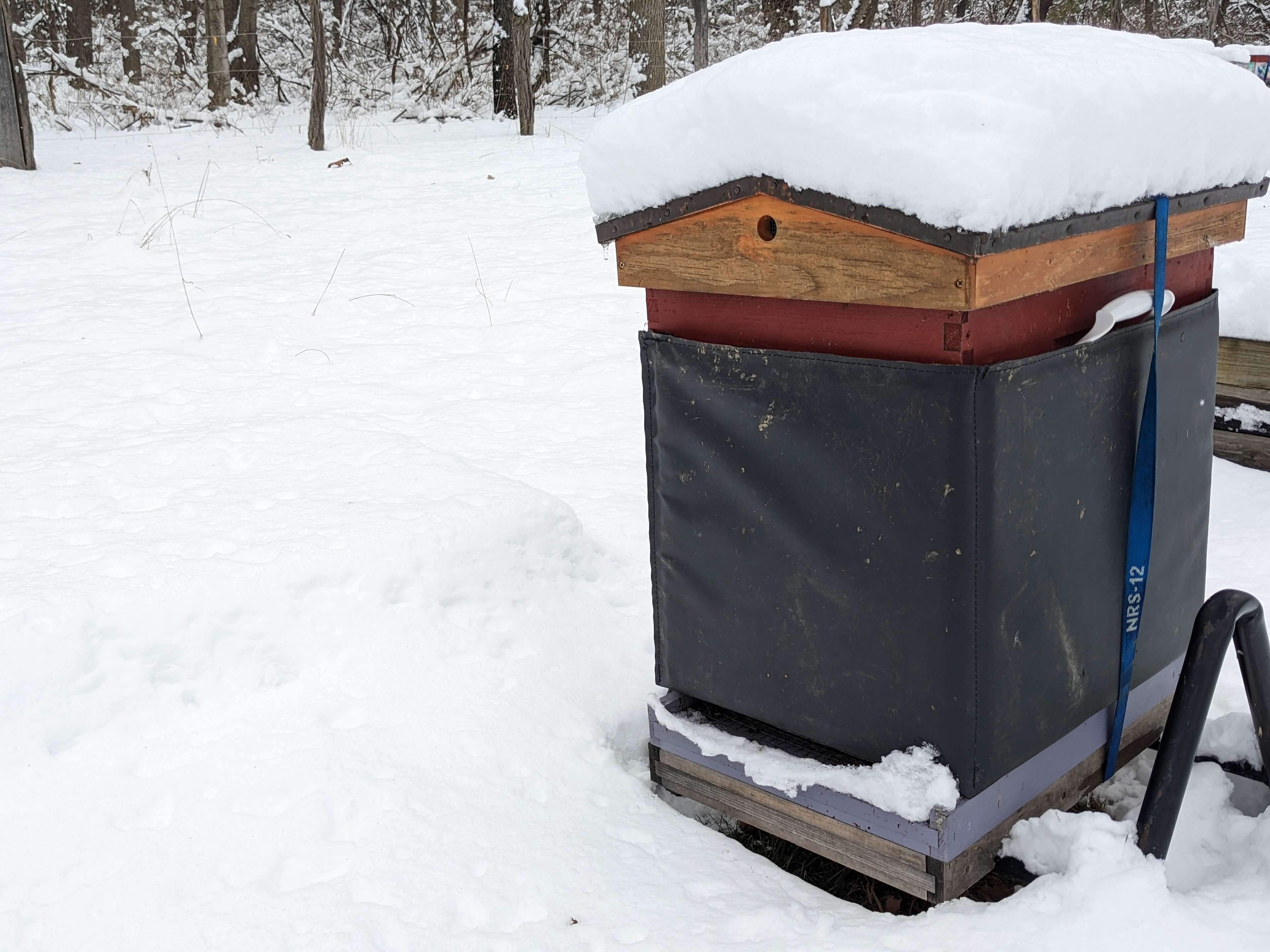 A insulated hive for winter with snow piled on the top